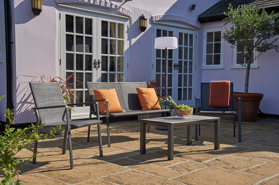 Aluminium garden sofa, lounge armchairs and coffee table sitting on a patio.