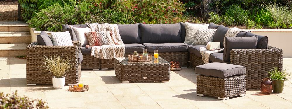 Rattan garden dining set (oval dining table with eight dining armchairs) on a sunny patio with a large parasol.